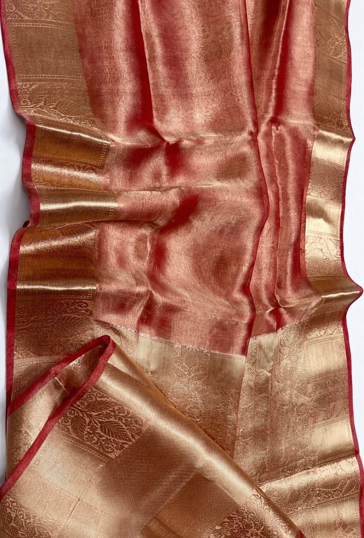Silky fabric with gold and red patterns on a white background