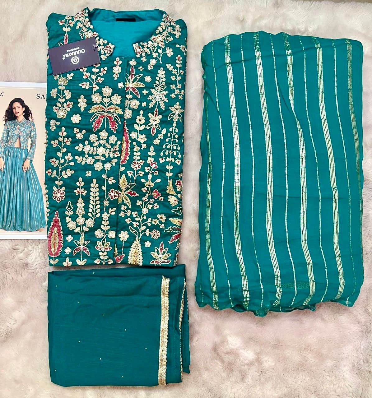 Teal fabric with floral patterns and striped design on a textured surface.