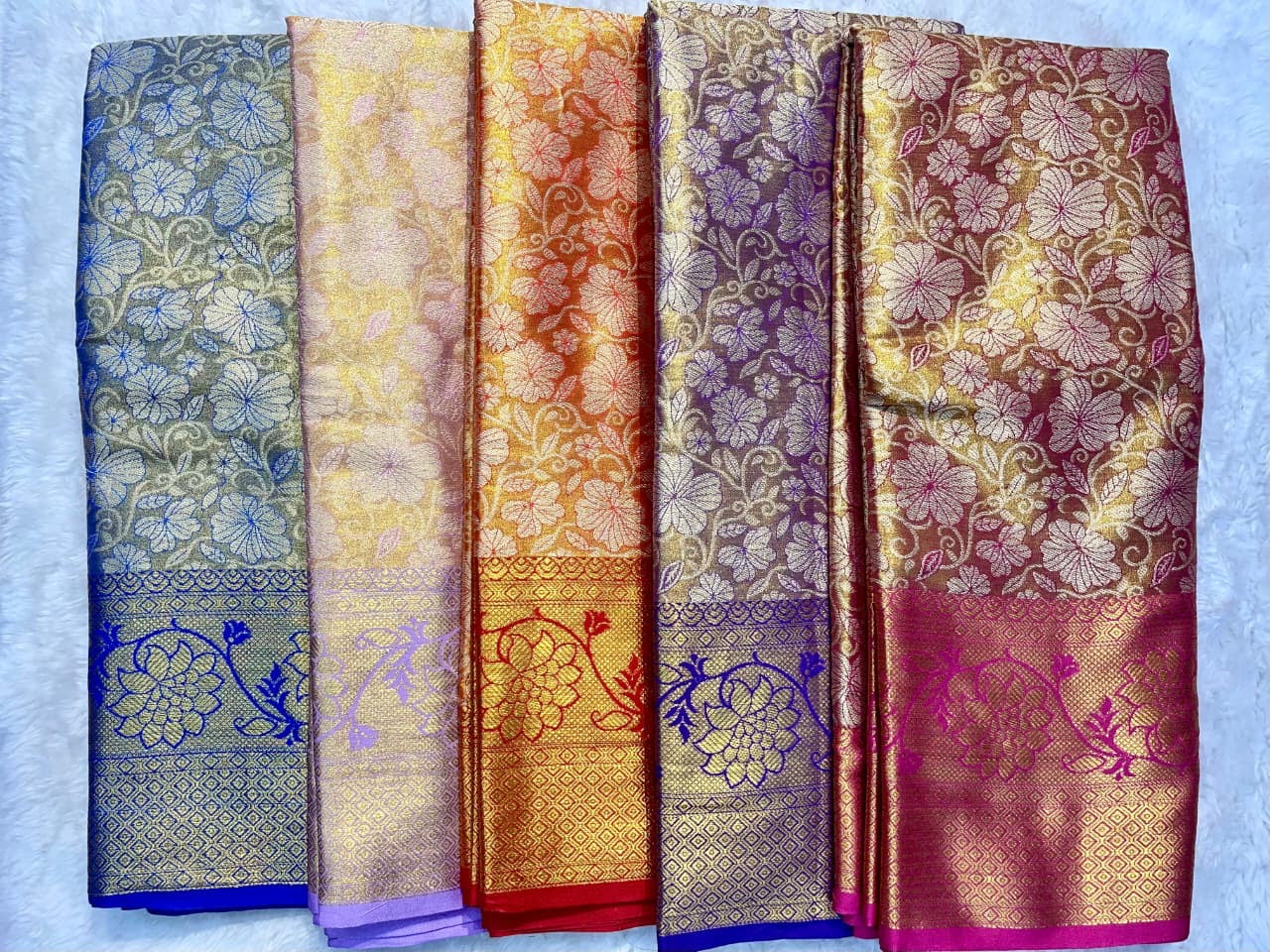 Five floral patterned scarves in different colors on a light blue background