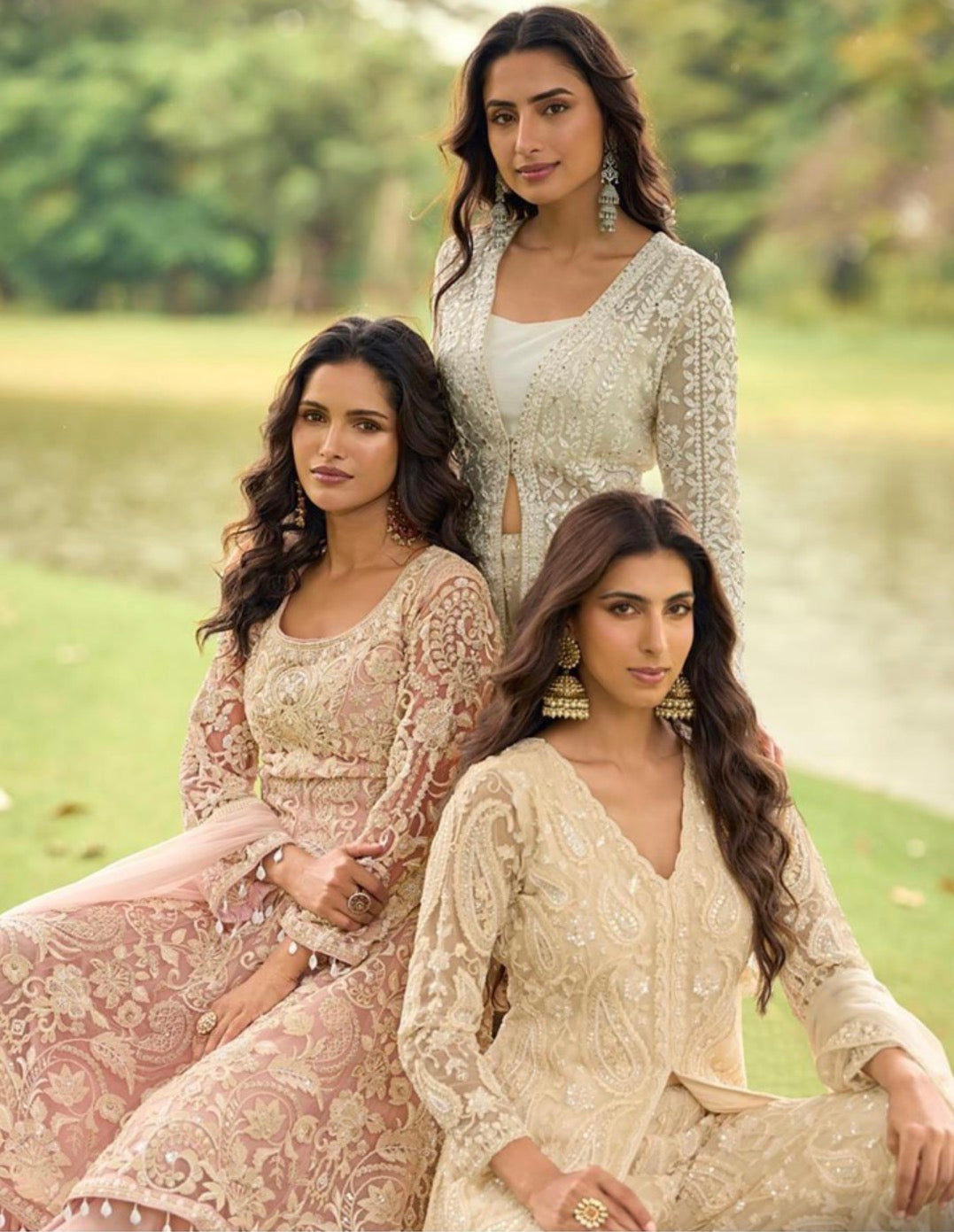 Three women in traditional embroidered dresses standing outdoors with a natural background.