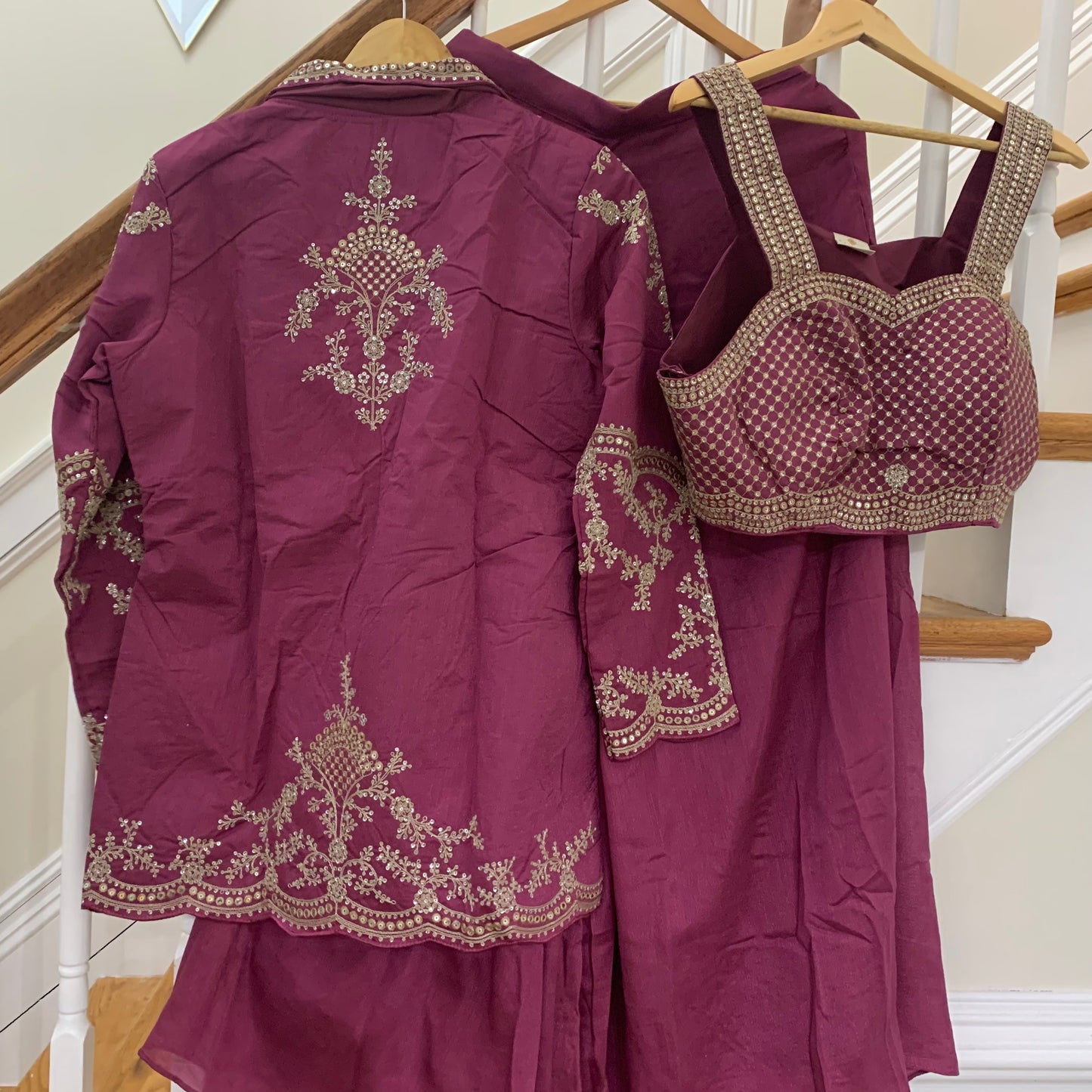 Maroon traditional outfit with intricate embroidery on a staircase