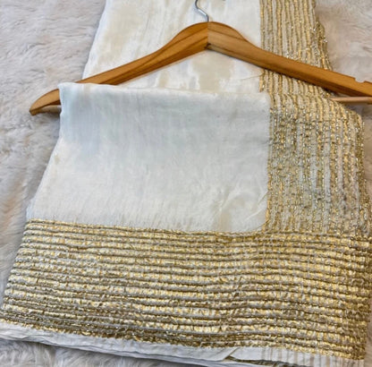Gold and white fabric on a wooden hanger against a neutral background