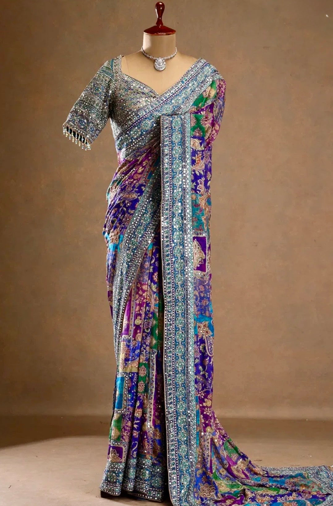 Colorful saree with intricate patterns on a mannequin against a beige background
