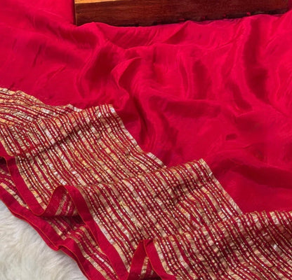 Red fabric with gold patterns draped over a wooden surface