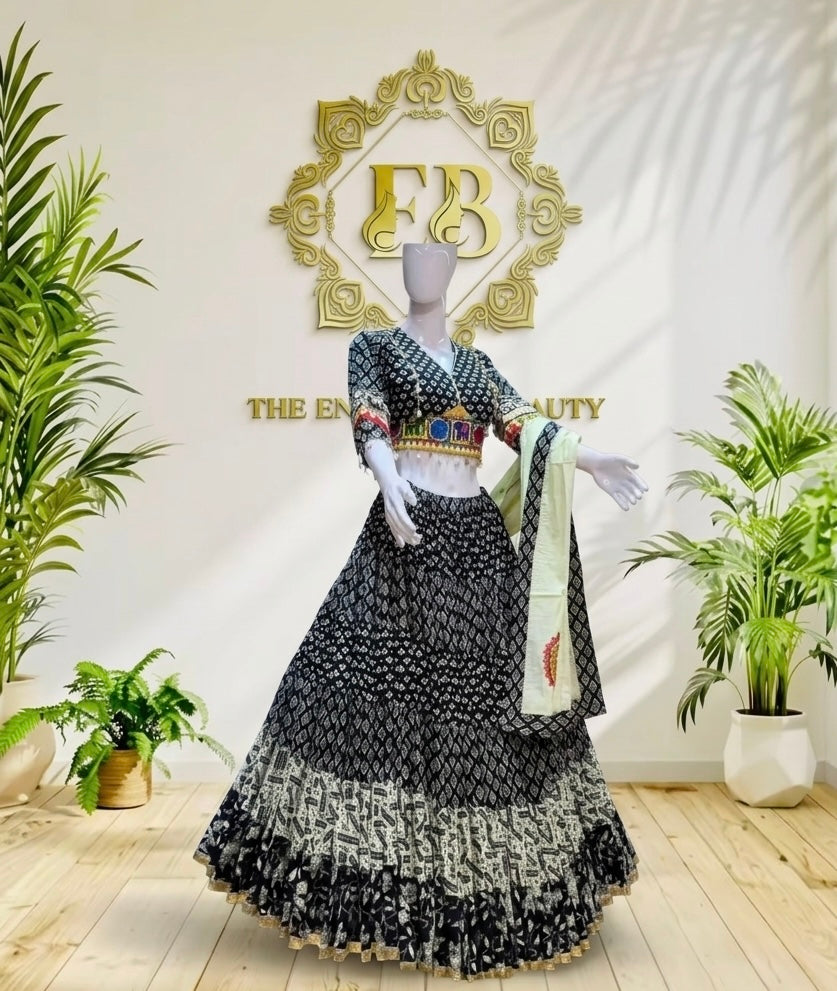 A black and white patterned traditional Indian outfit displayed on a mannequin in an indoor showroom. The outfit includes a flared skirt, a patterned top, and a light green dupatta with a red leaf motif.