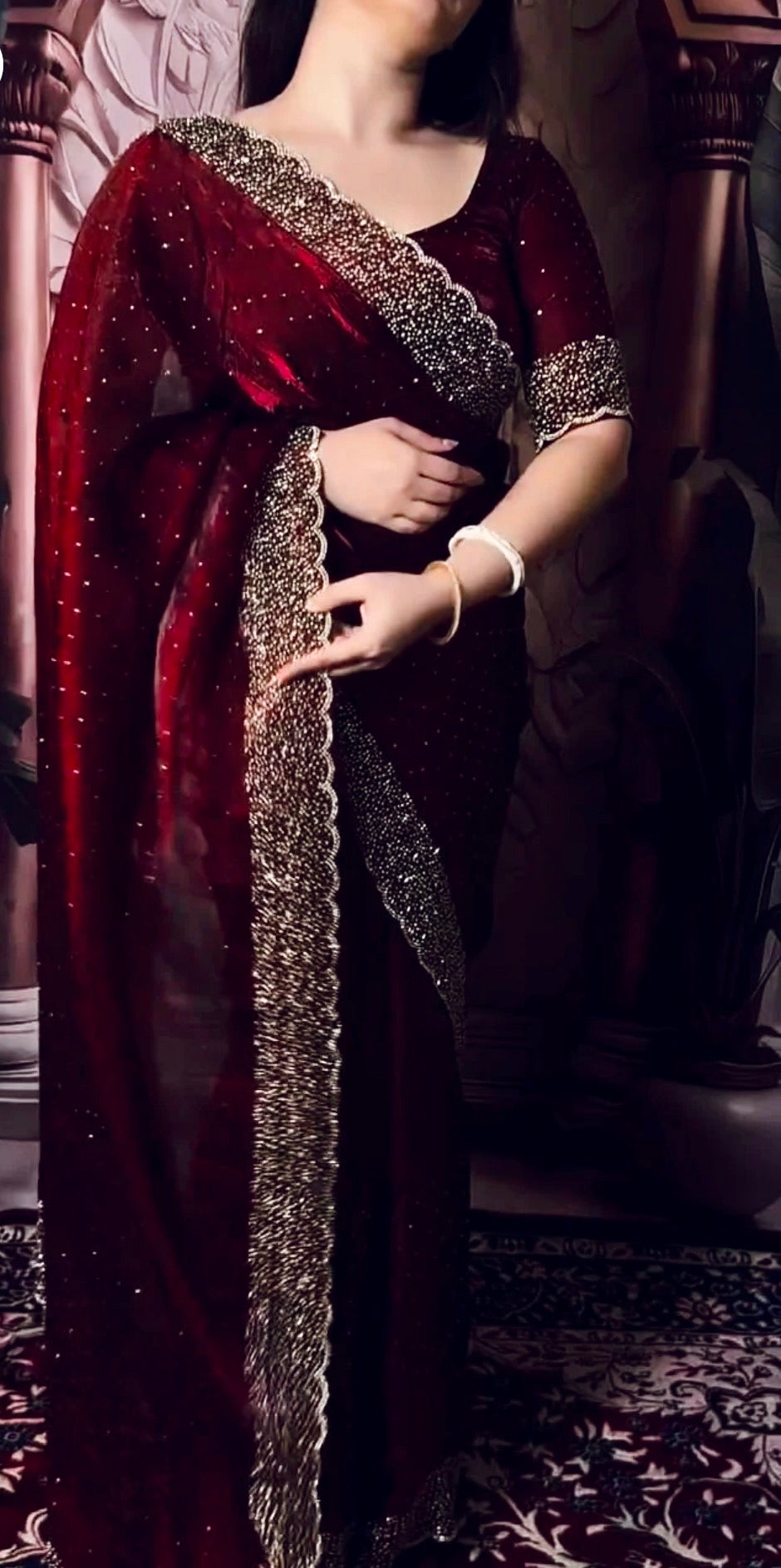 Woman wearing a red saree with gold border indoors