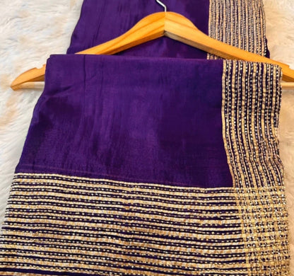 Purple fabric with gold and black pattern on a hanger against a textured surface