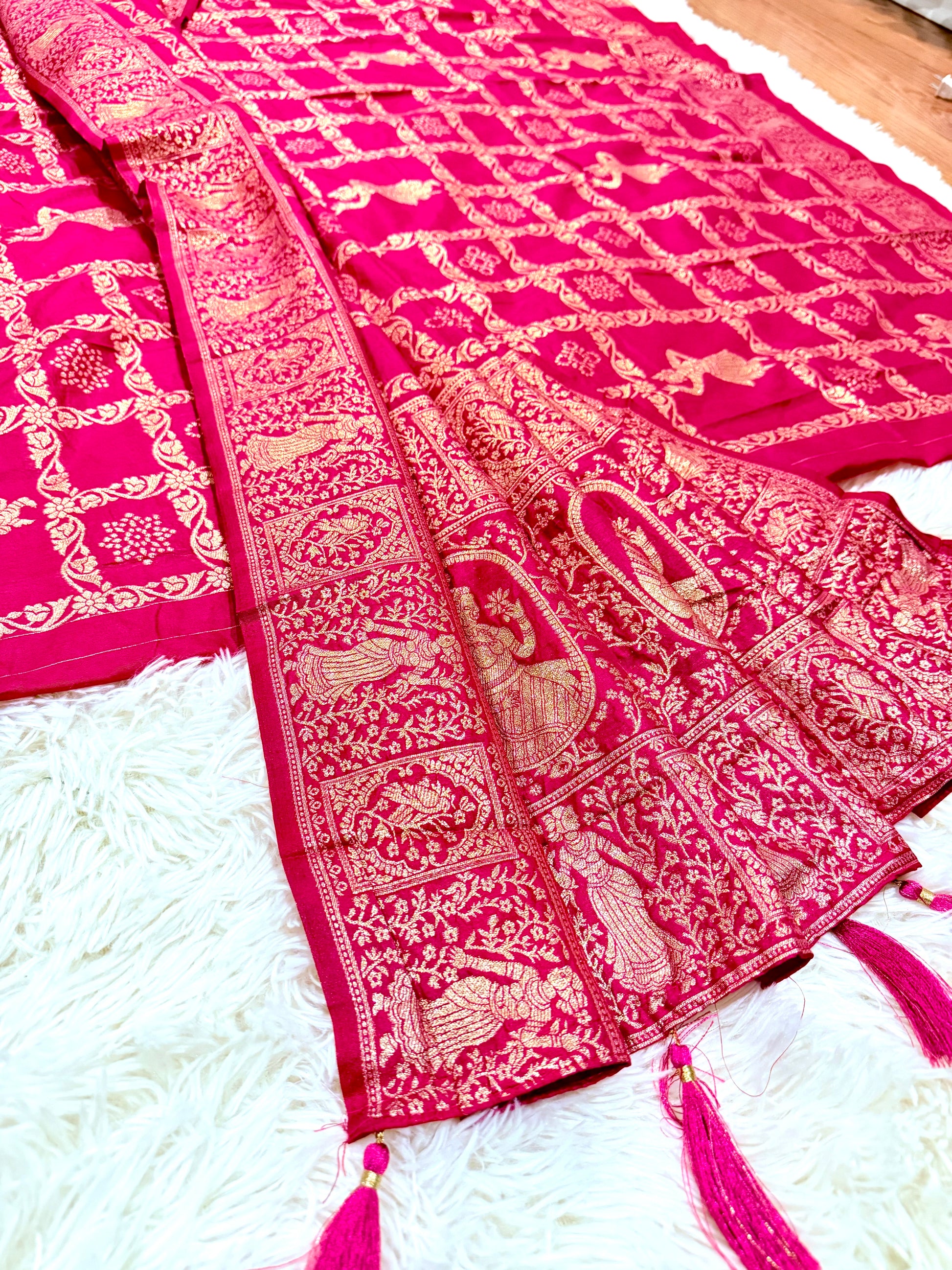 Pink saree with intricate patterns on a white surface