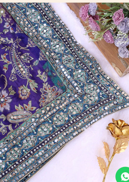 Decorative fabric with intricate patterns on a white surface with flowers and a gold leaf.