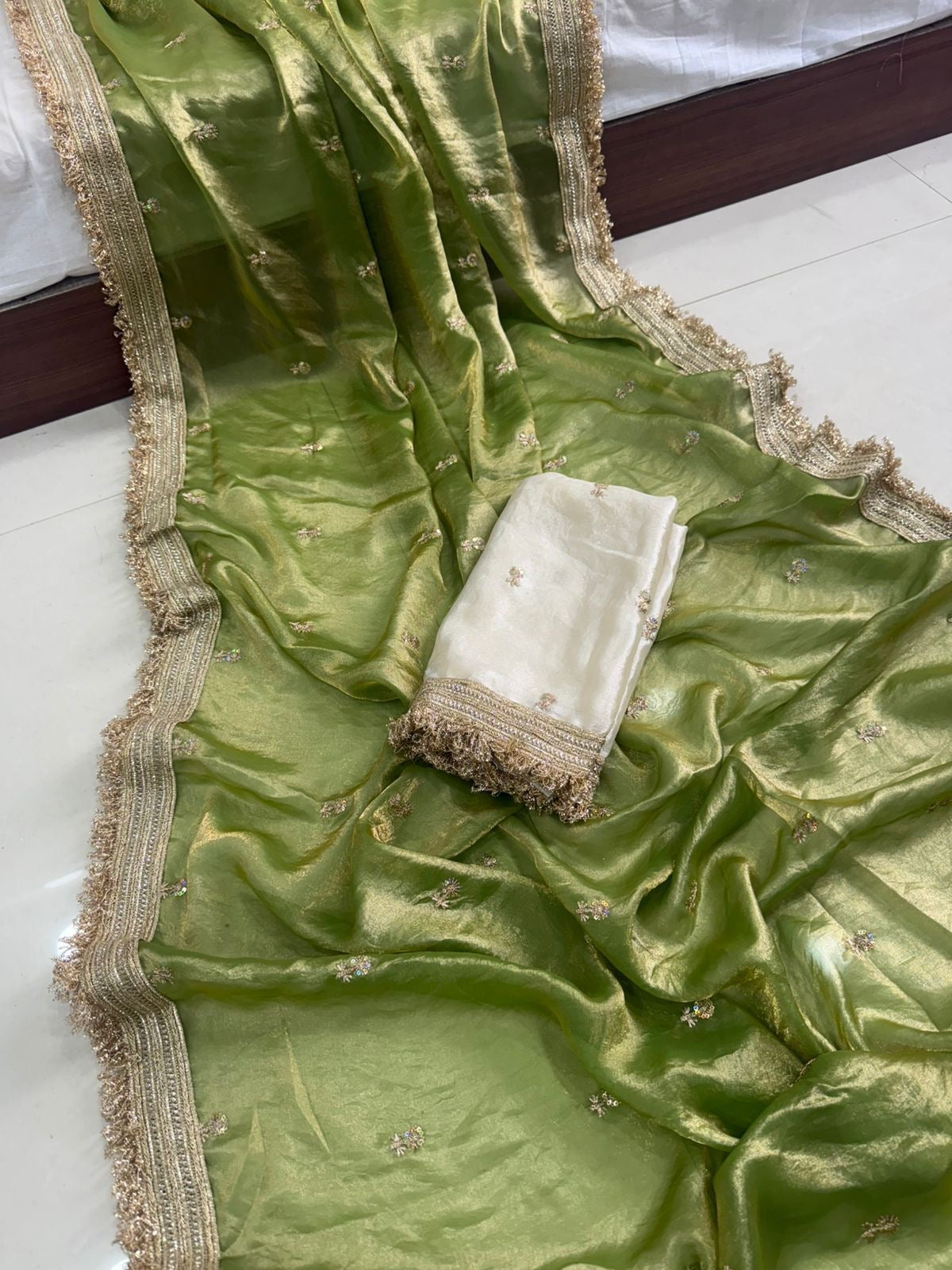 Green fabric with gold border and white folded item on a white surface