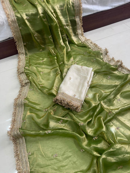 Green fabric with gold border and white folded item on a white surface