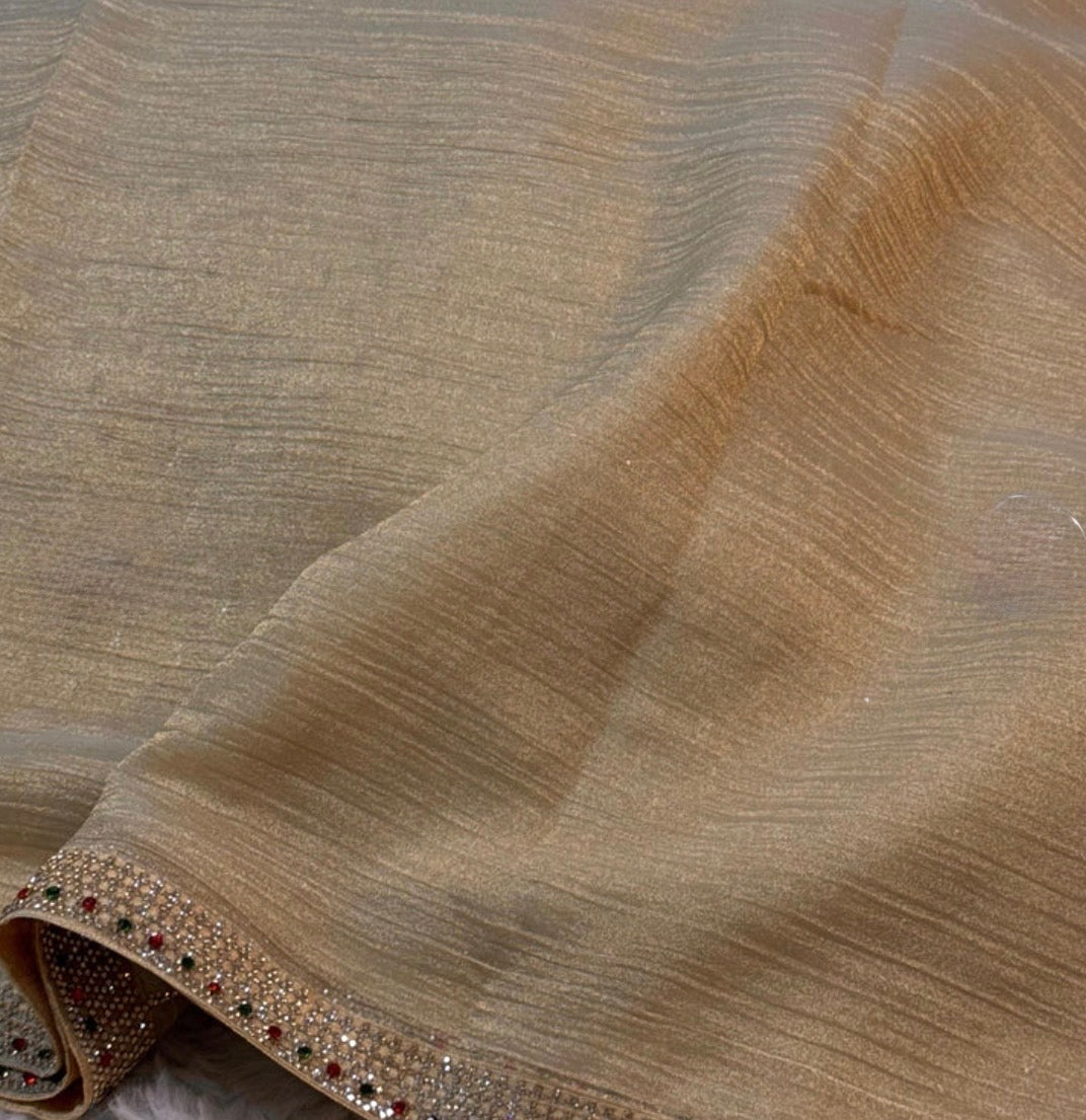 Close-up of beige fabric with a decorative border featuring small stones.