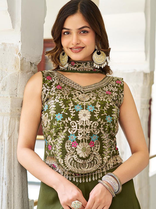 Woman wearing a green embroidered top with floral patterns indoors.