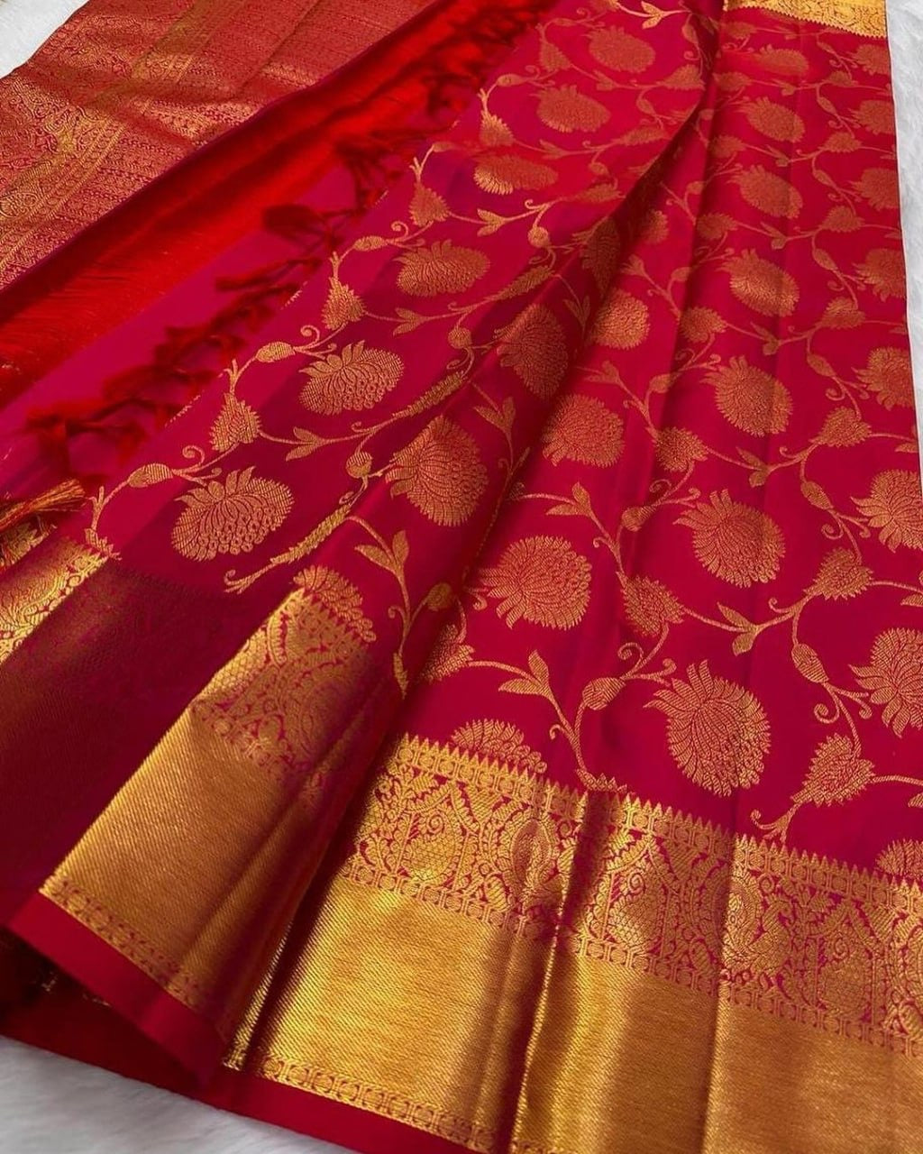 Red saree with gold floral patterns on a white background