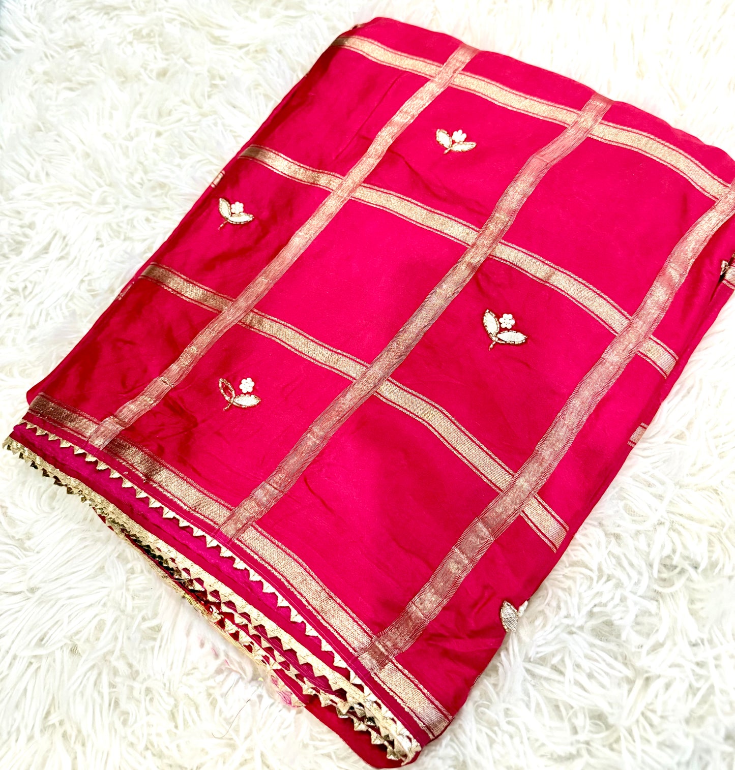 Red saree with gold patterns on a white textured background