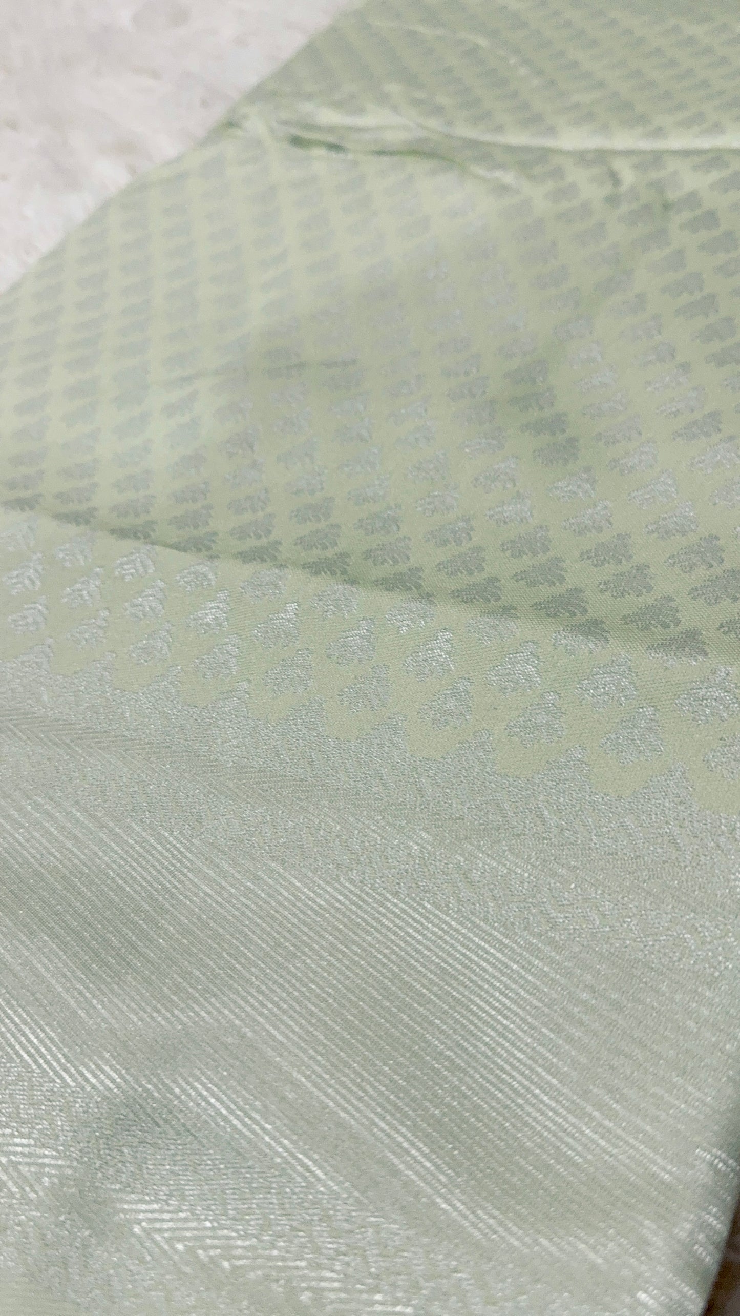 Close-up of a textured light green fabric with a subtle pattern.