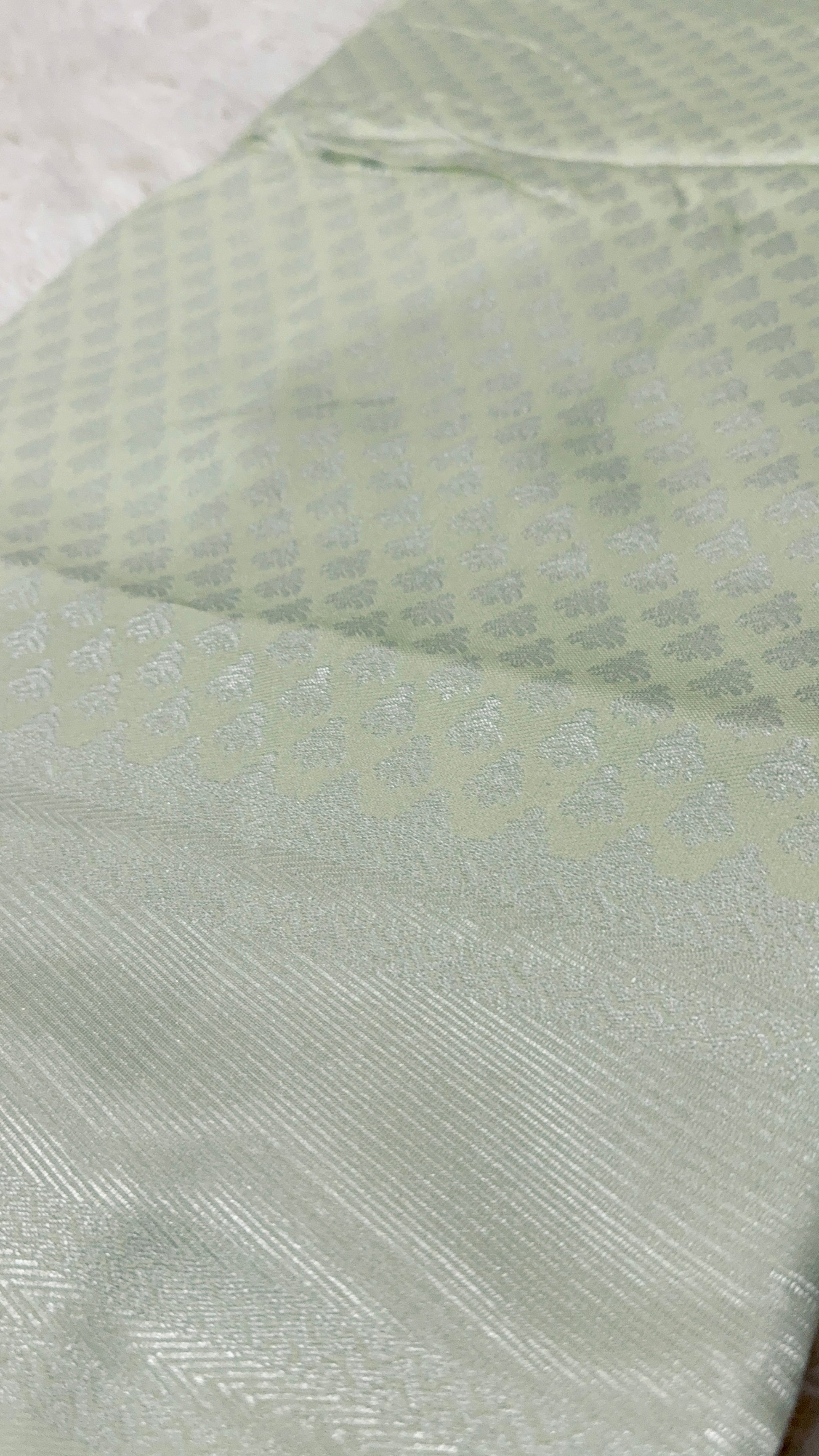 Close-up of a textured light green fabric with a subtle pattern.