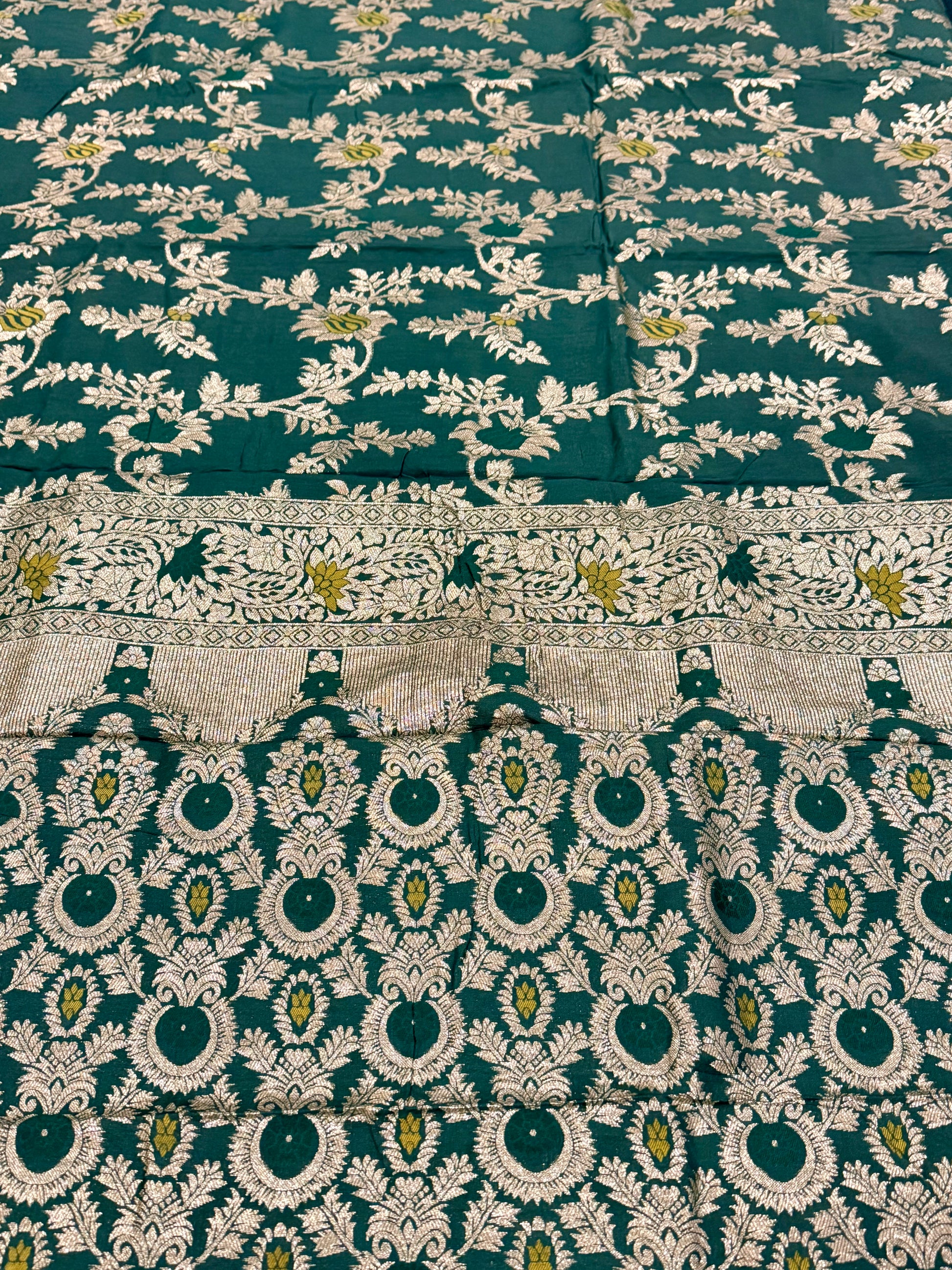Green fabric with intricate white and gold embroidery