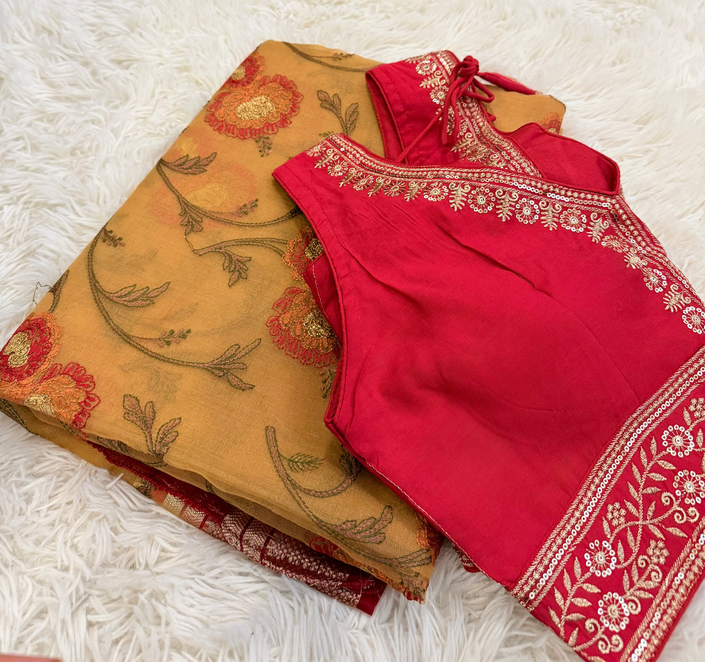Red and beige traditional outfits with floral patterns on a white textured surface