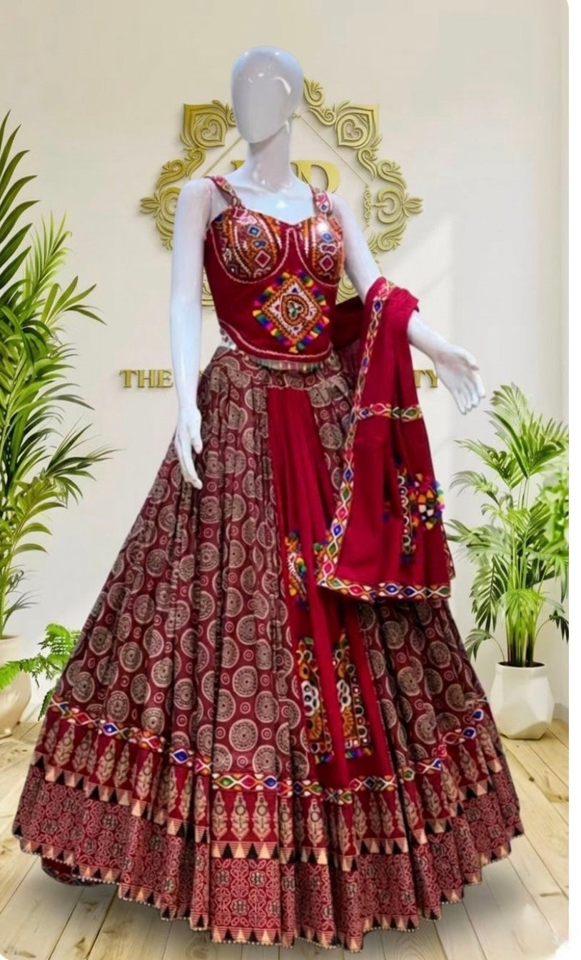 A red and gold printed Indian ethnic lehenga choli set displayed on a white mannequin, featuring a heavily embroidered red choli, a flared patterned skirt, and a matching dupatta.