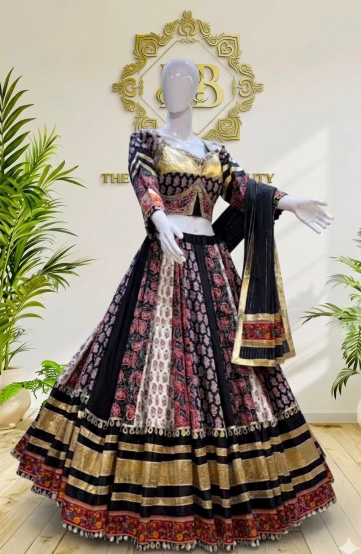 A traditional Indian ethnic wear set consisting of a black, gold, and red patterned lehenga choli with a dupatta, displayed on a white mannequin in a boutique setting.