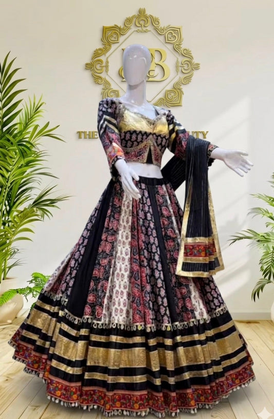 A traditional Indian ethnic wear set consisting of a black, gold, and red patterned lehenga choli with a dupatta, displayed on a white mannequin in a boutique setting.