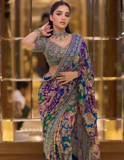 Woman in a colorful saree with intricate patterns in a reflective gold interior setting