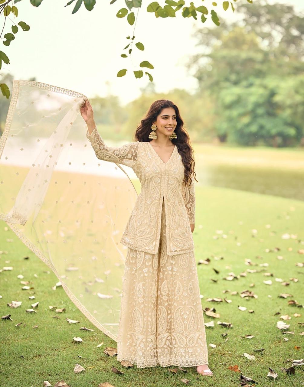 Woman in a traditional outfit standing outdoors with greenery in the background