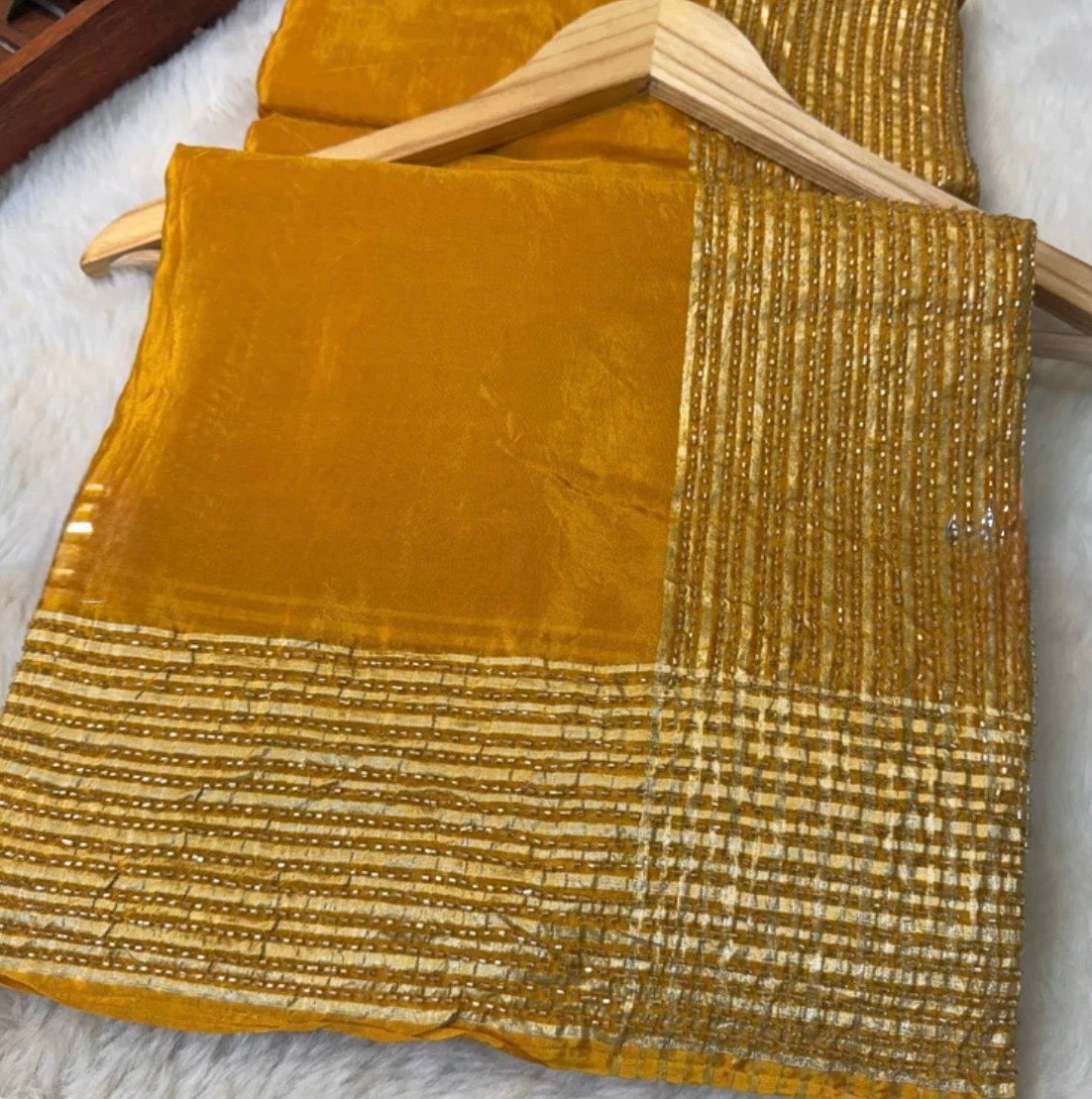 Gold fabric with textured pattern on a hanger against a neutral background