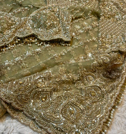 Close-up of intricately embroidered fabric with gold thread and beads.