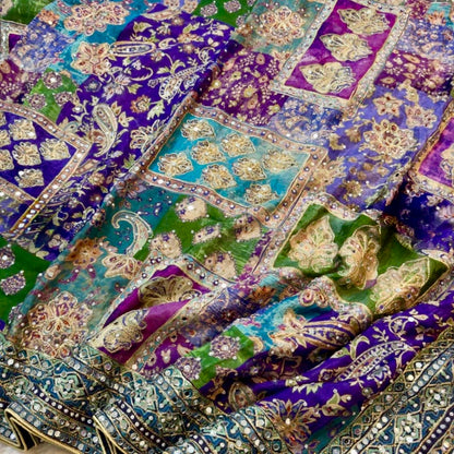 Colorful embroidered fabric with intricate patterns on a green background