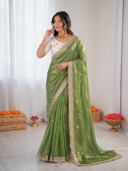 Woman wearing a green saree with a white blouse in a minimalistic setting.