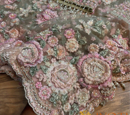 Close-up of floral embroidery with pink and green colors on a fabric background.