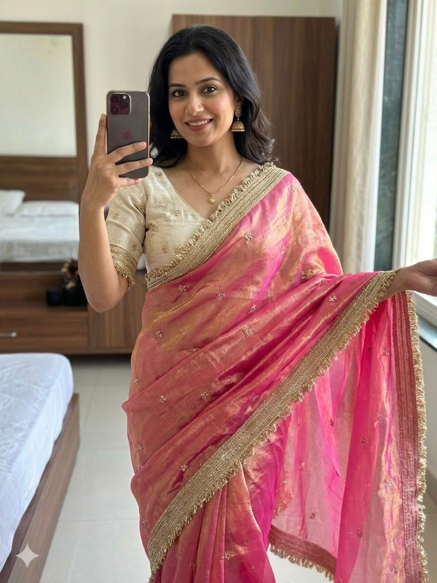 Woman in a pink saree taking a mirror selfie in a bedroom.
