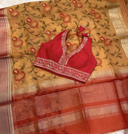Red blouse with floral patterns on a beige saree with similar design