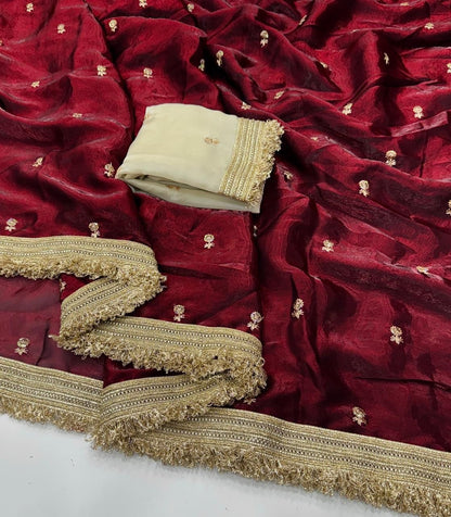 Red fabric with gold embroidery and a folded beige fabric on top