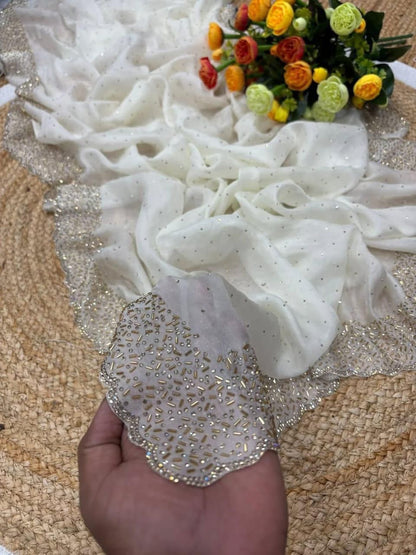 White lace fabric with a hand holding a decorative item, and a bouquet of flowers in the background.