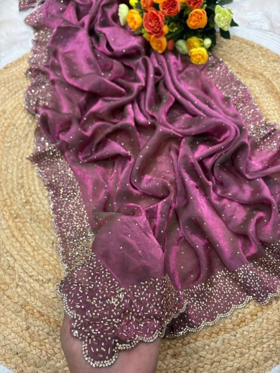 Purple fabric with gold embroidery on a textured surface with flowers in the background