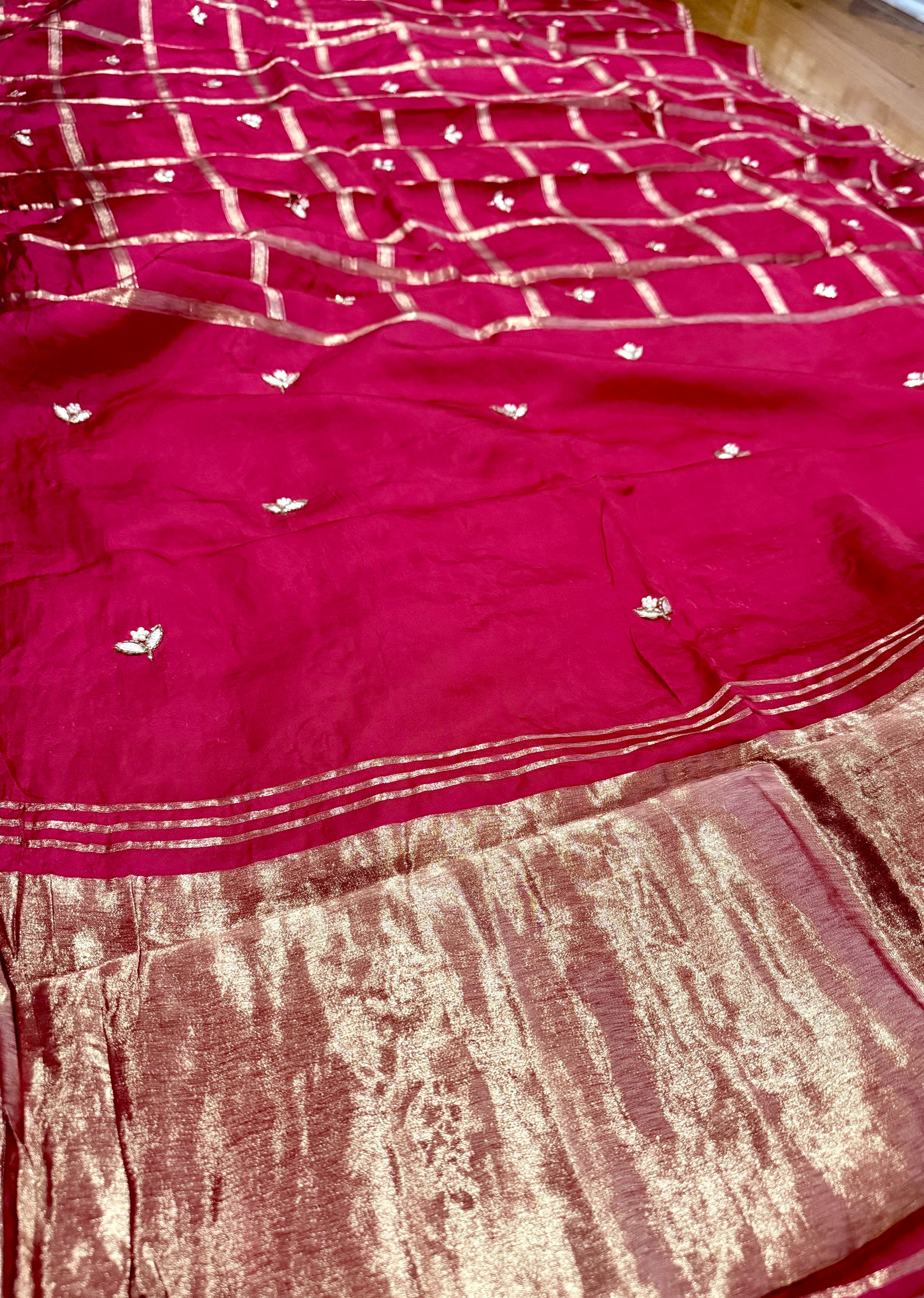 Red saree with white patterns on a wooden floor