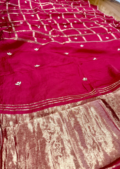 Red saree with white patterns on a wooden floor