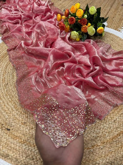 Pink velvet fabric with sequin details on a textured surface with flowers.