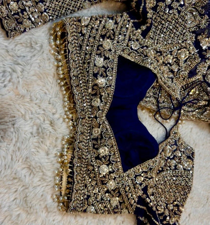 Close-up of a decorative fabric with gold embroidery and a blue center on a beige background