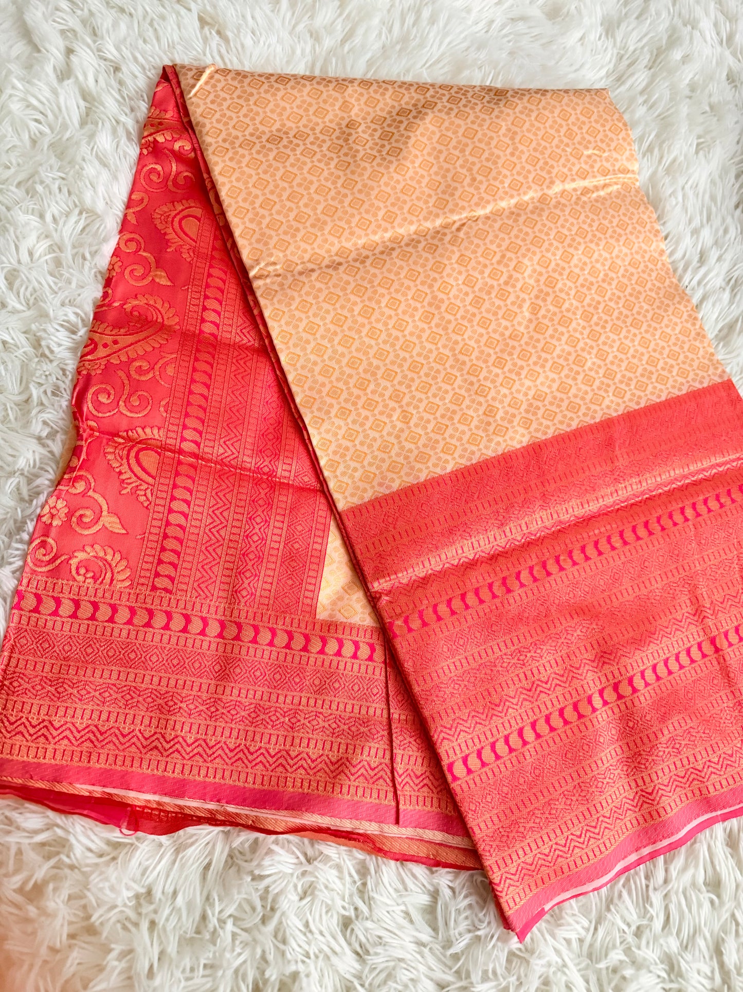 Red and gold saree with intricate patterns on a white textured surface