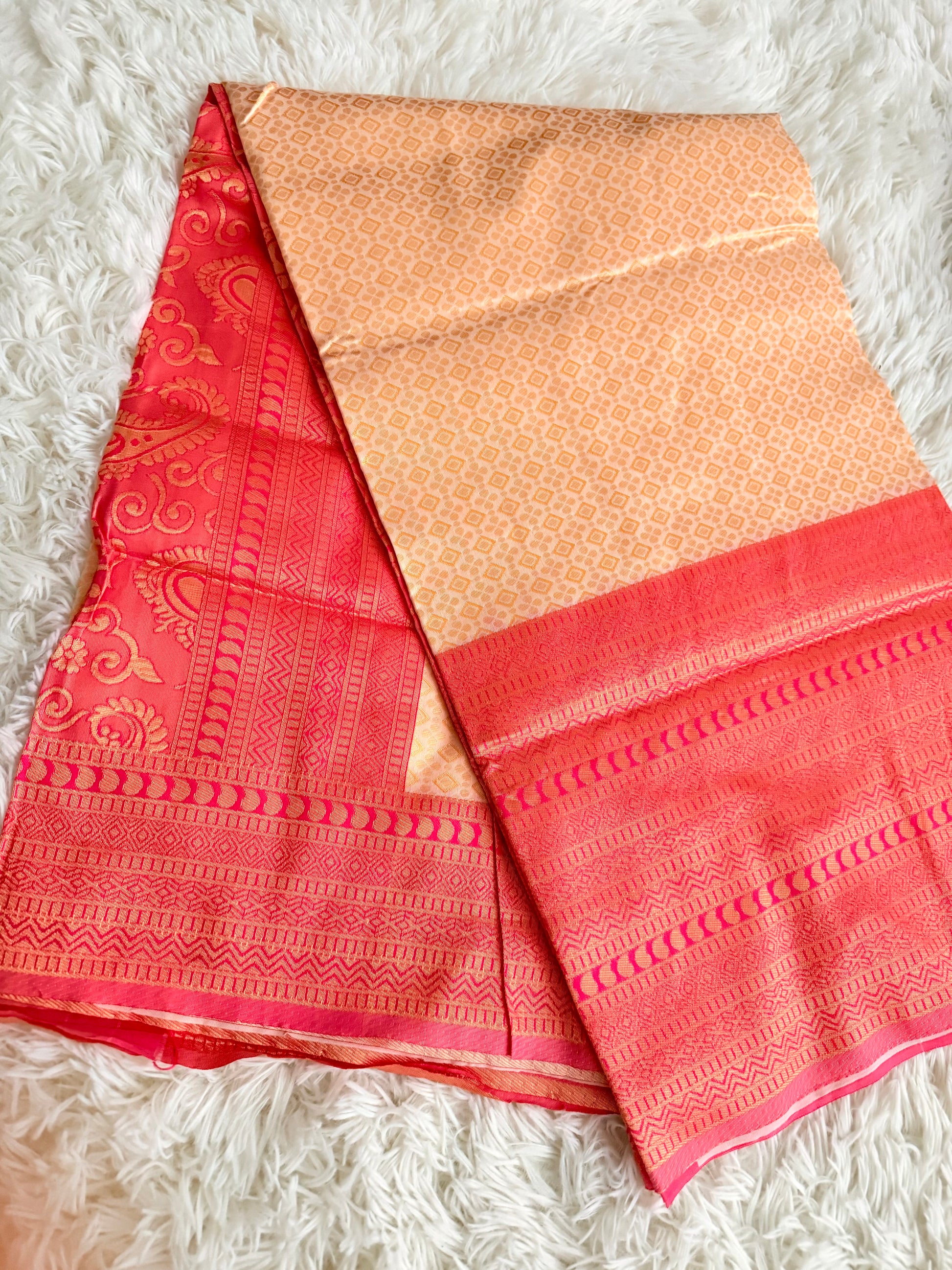 Red and gold saree with intricate patterns on a white textured surface