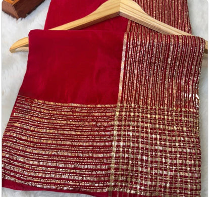 Red fabric with a textured pattern draped over a wooden hanger on a light background