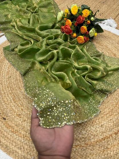 Green fabric with floral decorations held by a hand on a textured surface