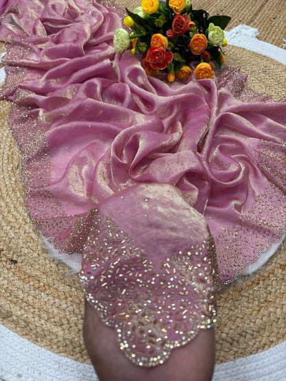 Pink fabric with glittery accents and a bouquet of flowers on a textured surface