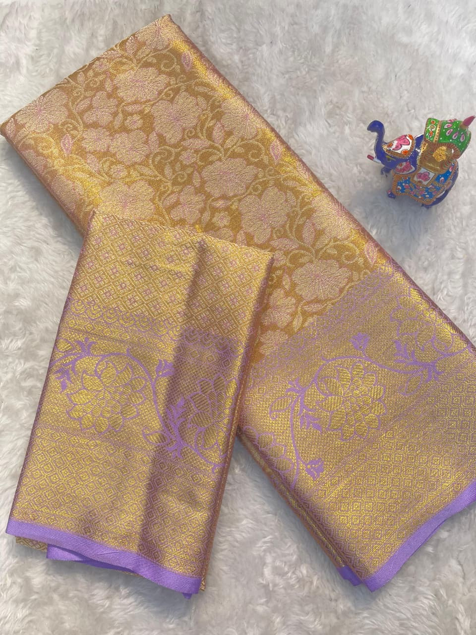 Gold and purple fabric with intricate patterns on a light gray background