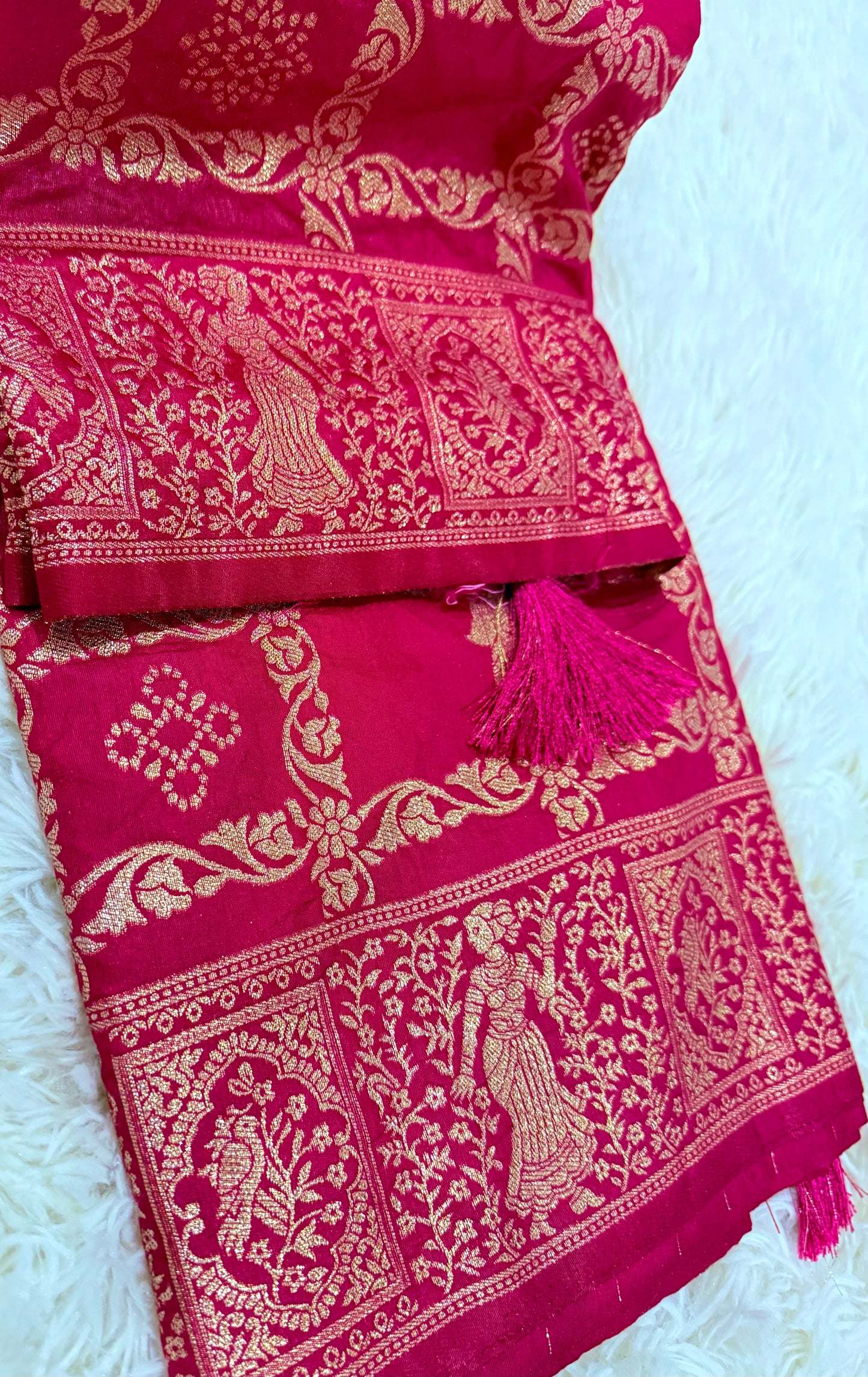Red fabric with gold embroidery and tassels on a white background