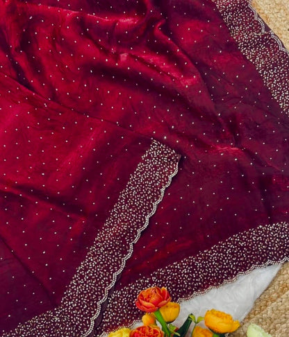Maroon fabric with bead border and flowers on a beige surface